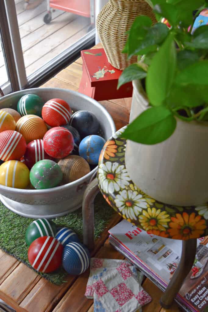 Colorful croquet balls in large metal colander as decor.
