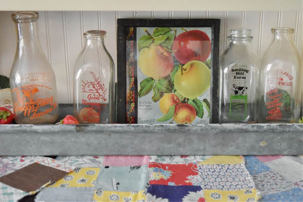 Vintage apple picture displayed with old milk bottle collection.