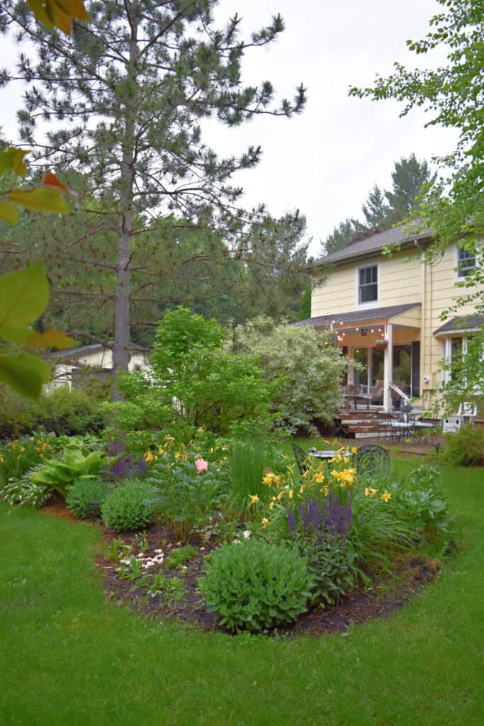 Perennial garden in yard of yellow house.