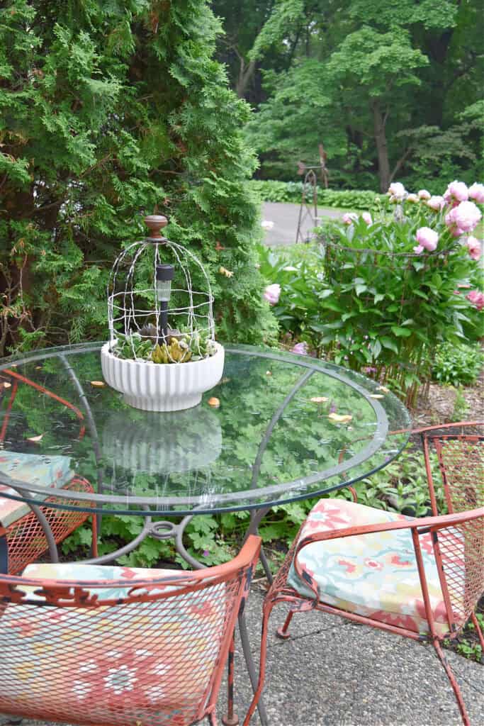 Glass top porch table and orange metal chairs.