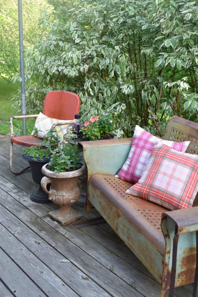 Vintage metal glider on porch and summer flowers.