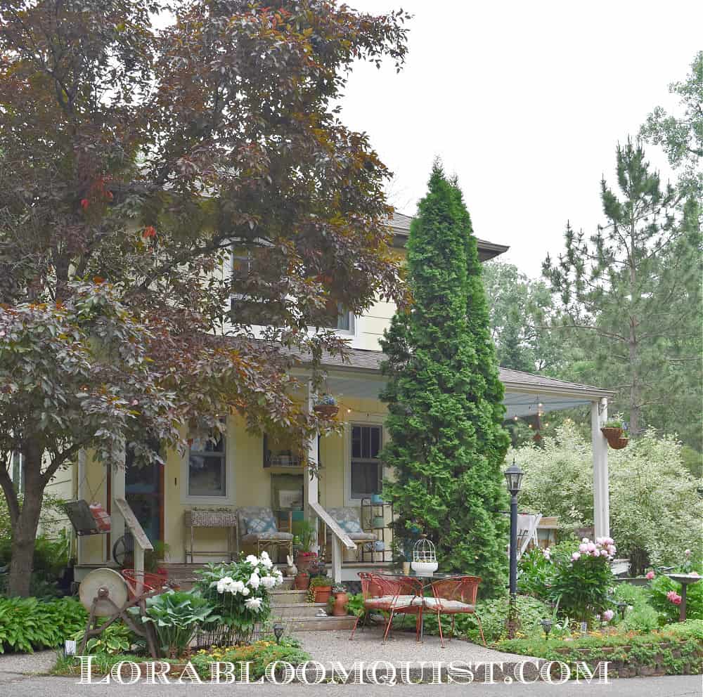 Vintage yellow farmhouse, surrounded by gardens.