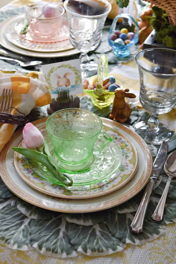 Green depression ware cup and saucer on vintage plates for Easter table setting.