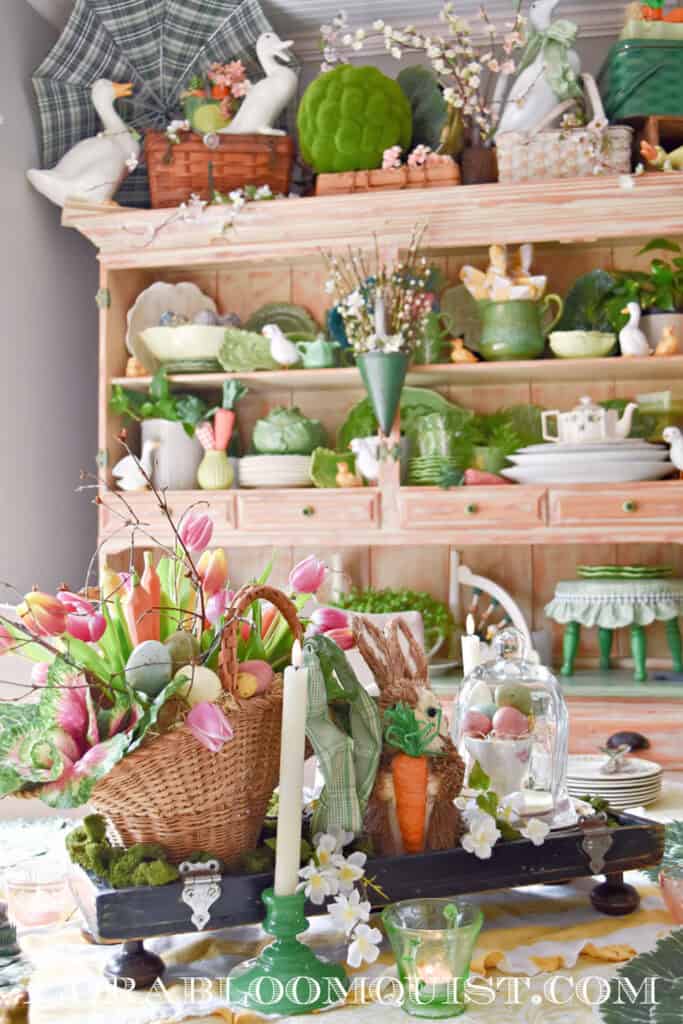 Spring decorated table and hutch with Easter bunny, cabbage ware and tulips.