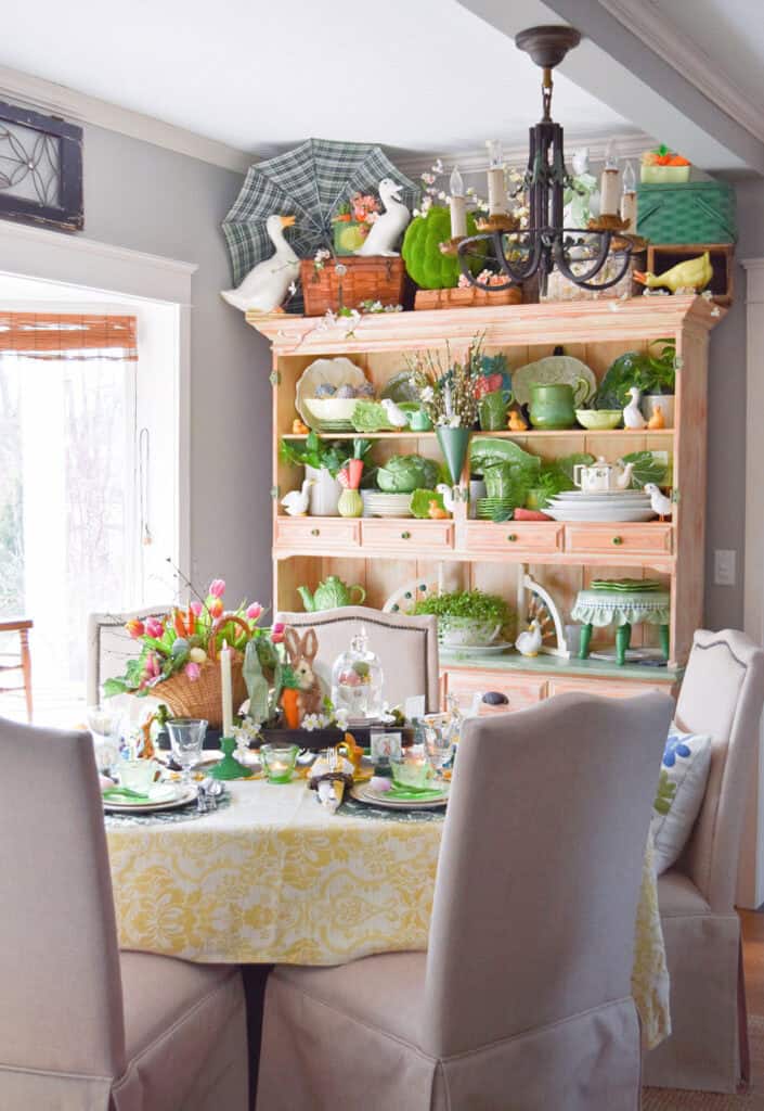 Spring decorated table and hutch with Easter bunny, cabbage ware and tulips.