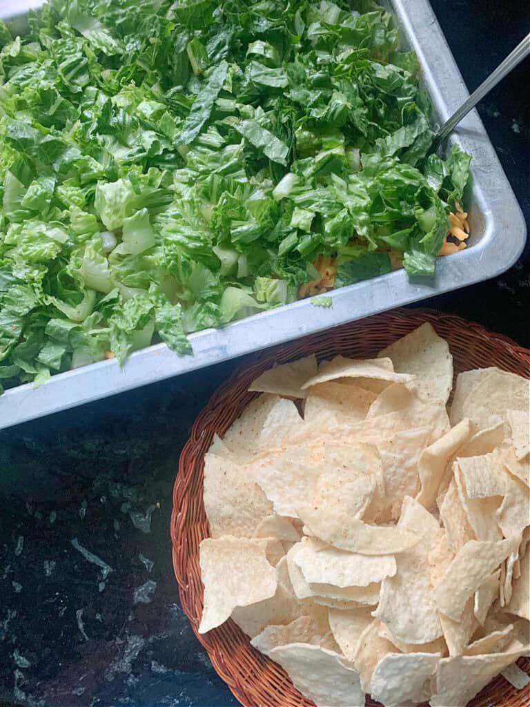 Layered taco dip with lettuce and tortilla chips.