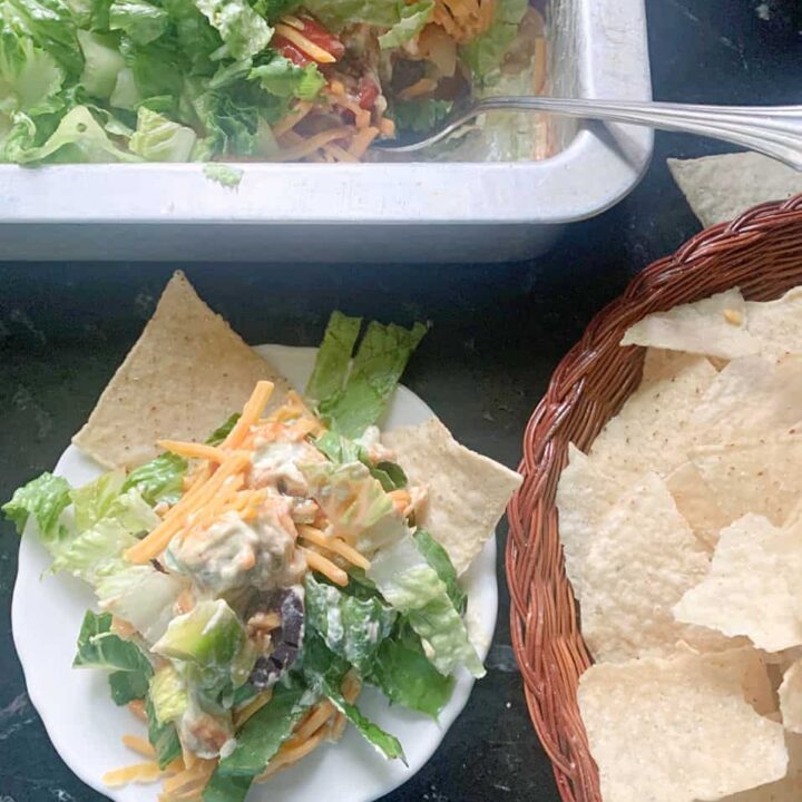 Serving layered taco dip with tortilla chips.