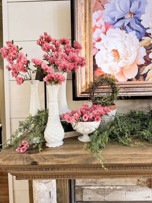 Pink flowers in milk glass vases on mantel