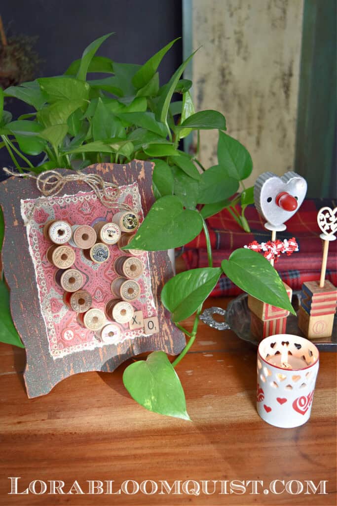 Vintage wooden thread spool Valentine art in craft room.
