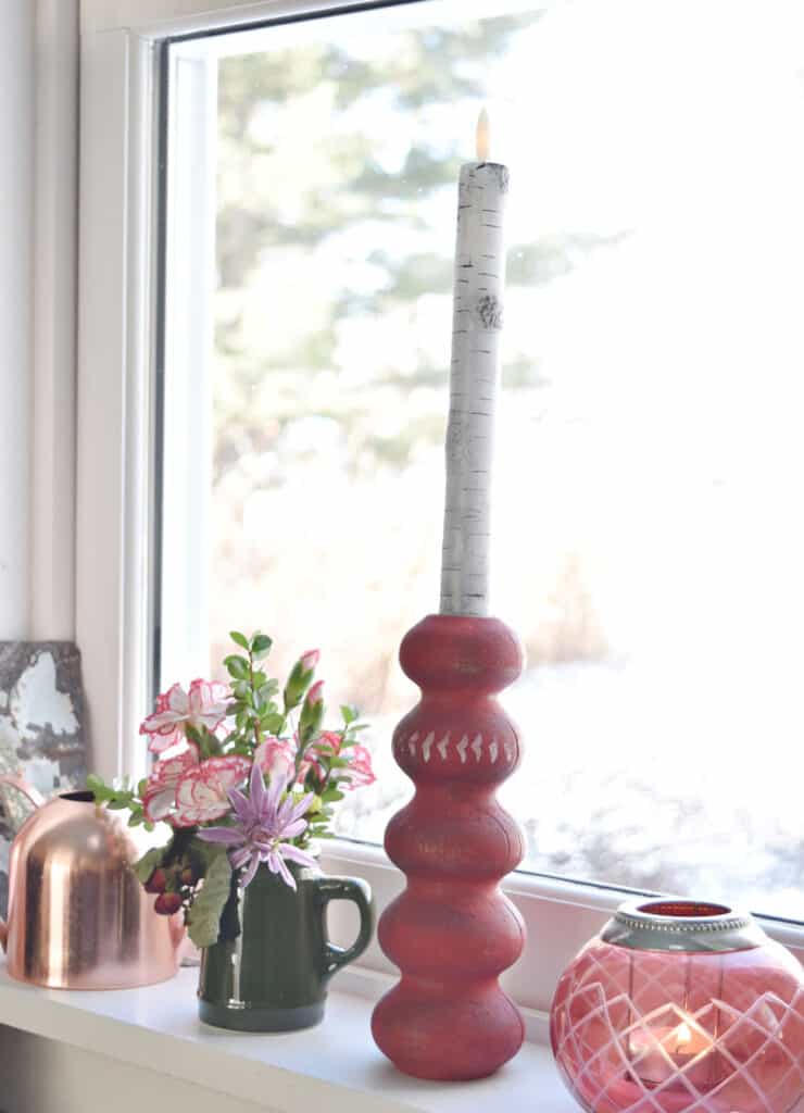 Upcycled spindle candlestick and flowers on windowsill.