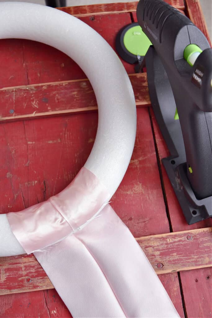 Wrapping satin ribbon around styrofoam wreath for DIY Valentines wreath.