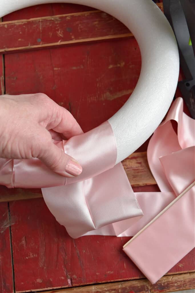 Wrapping satin ribbon around styrofoam wreath for DIY Valentines wreath.