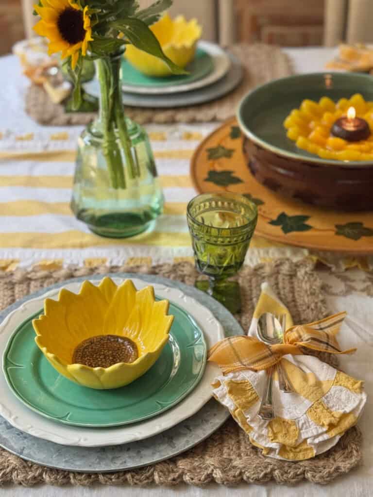 Sunflower bowls on green plates and yellow and white stripe linens.