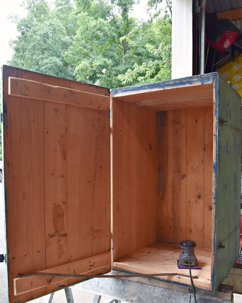 Sanding an Antique green wooden trunk.