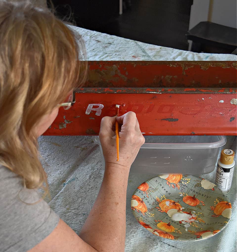 Woman painting words on old red wagon.
