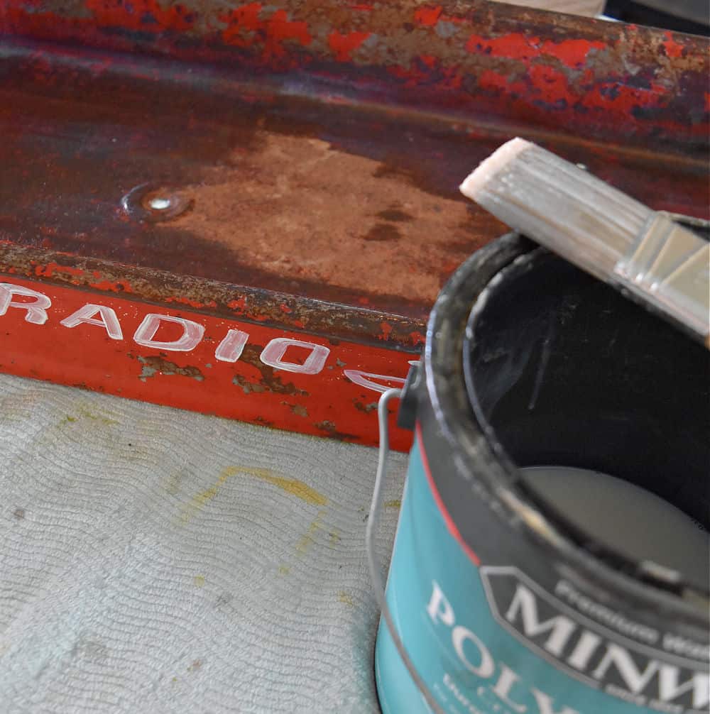 Brushing poly on an old metal red wagon.