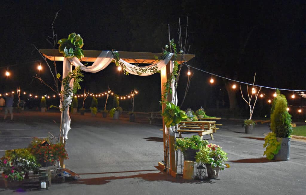Nighttime garden party wedding reception with lighted arbor.
