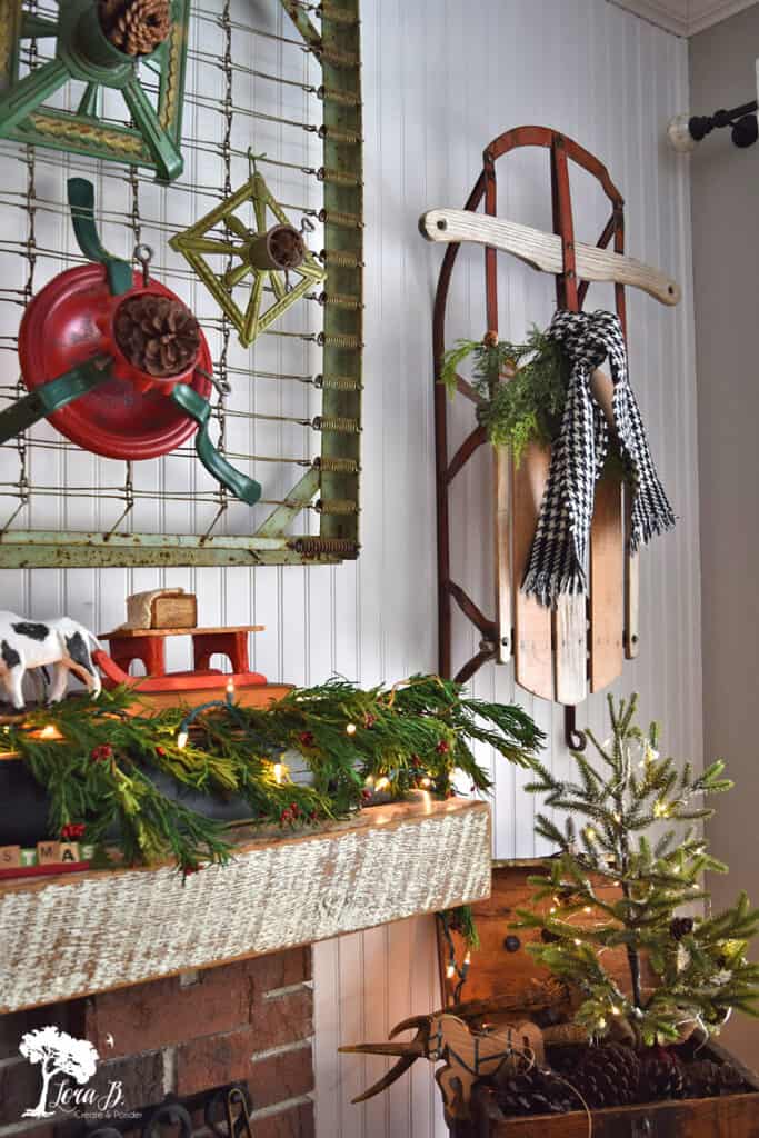 Christmas decorated mantel with tree stands and old sled.