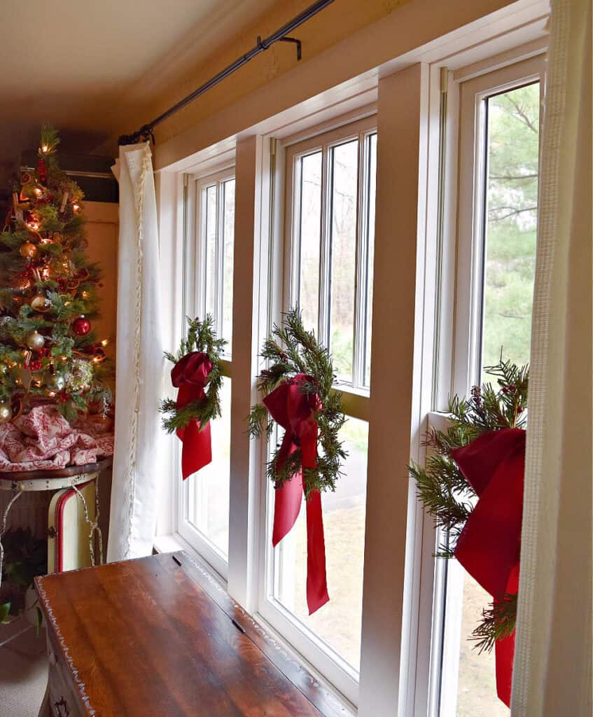 Windows decorated for Christmas with wreaths and ribbons.