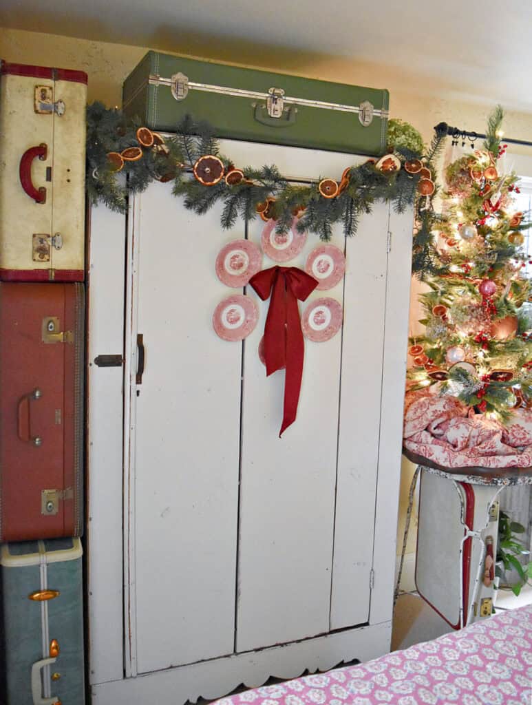 White cupboard decorated for Christmas with vintage finds.